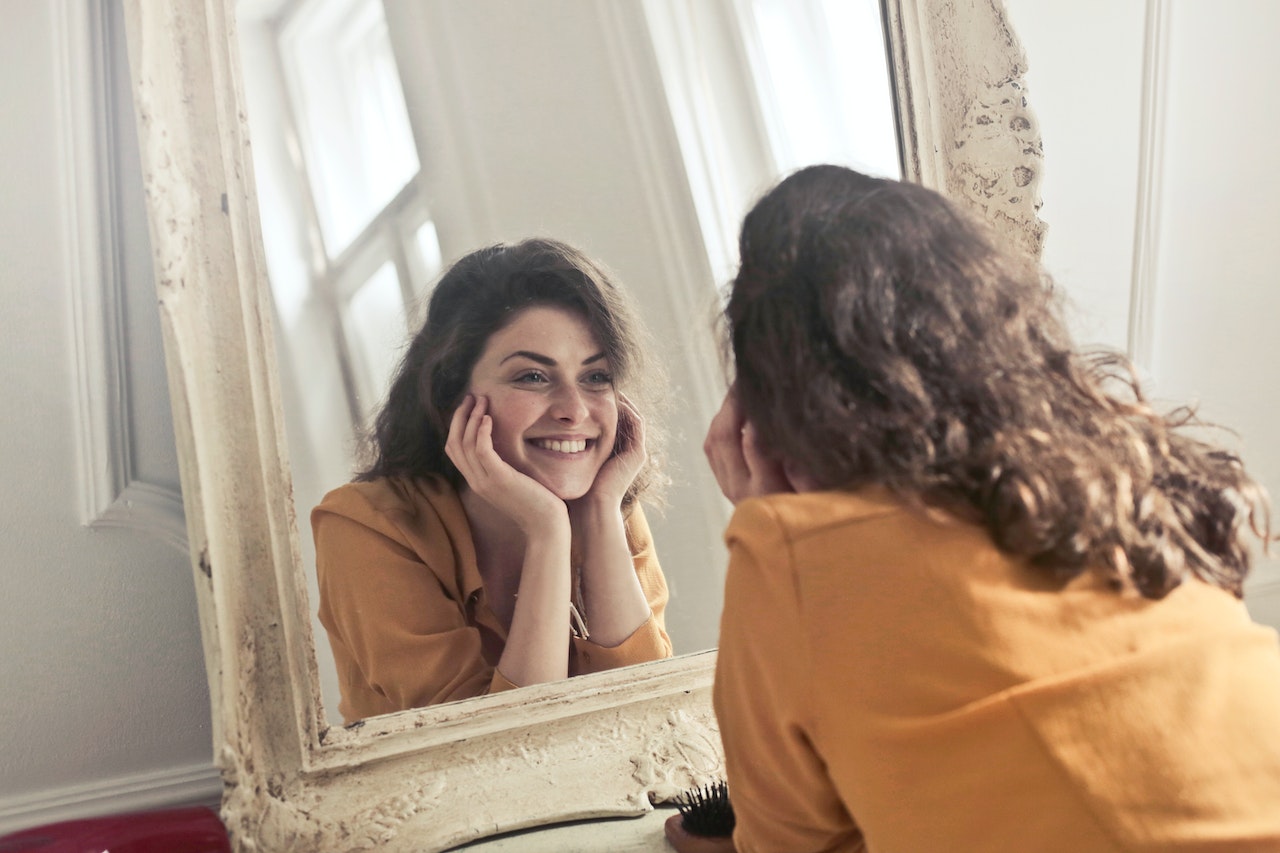 Woman looking in mirror thinking about self worth